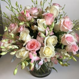Pink and white roses arranged in a clear glass vase