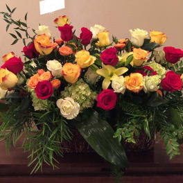 Large mixed rose arrangement with yellow lilies in a basket