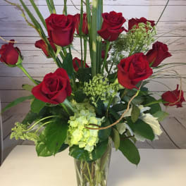 Red roses and pale green hydrangea in a clear glass vase