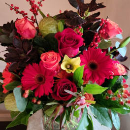 Bouquet of pink roses and red gerbera daisies in a glass vase