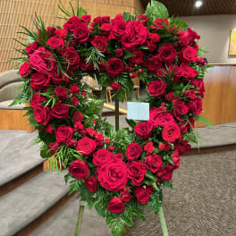 Heart-shaped wreath of red roses on a stand