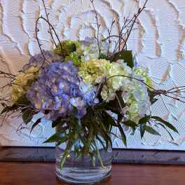 Blue and white hydrangea arrangement in a clear glass vase