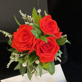 Red rose boutonniere with green leaves and small white accents