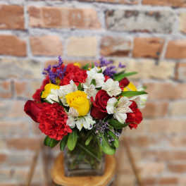 Bouquet of red and yellow roses with white alstroemeria in a glass vase