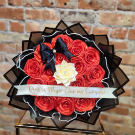 Bouquet of red roses with a white flower center and black ribbon