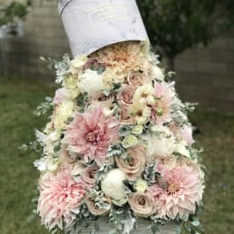 Pastel floral arrangement in a hatbox with pink and cream blooms