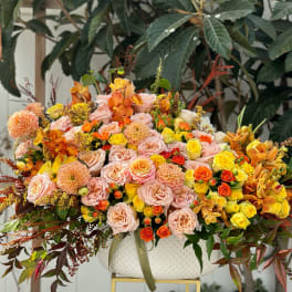 Large mixed floral arrangement in a white bowl vase with pink, yellow, and orange blooms