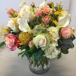 Bouquet of pink and white roses with yellow filler in a glass vase