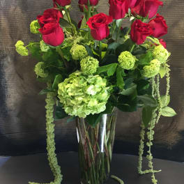 Red roses and green hydrangea in a tall glass vase