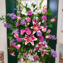 Tall floral spray with pink roses, white lilies, and purple blooms