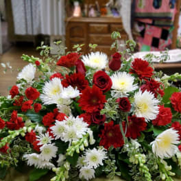 Low floral arrangement of red and white flowers with greenery