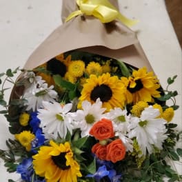 Bouquet of sunflowers, white daisies, and orange roses wrapped in brown paper