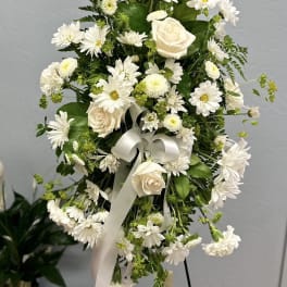White floral standing spray with roses, daisies, and ribbon