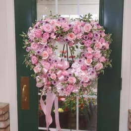 Heart-shaped pink floral wreath on a stand with ribbon