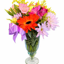 Colorful mixed bouquet in a glass vase with a purple ribbon