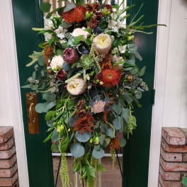 Large floral wreath with mixed blooms and greenery on a stand