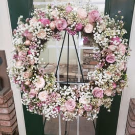 Heart-shaped floral wreath with pink roses and white baby's breath on an easel
