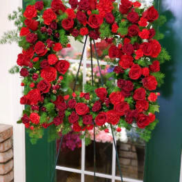 Heart-shaped wreath of red roses and carnations on a stand