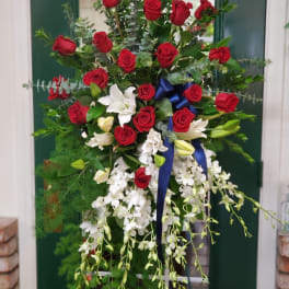 Tall floral spray with red roses, white orchids, and a blue ribbon