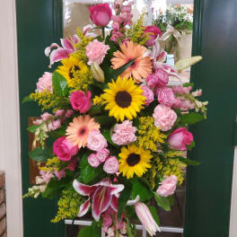 Large standing floral spray with pink, yellow, and peach blooms