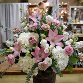 Pink lilies and white hydrangeas in a dark woven basket