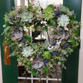 Heart-shaped succulent wreath on an easel with mixed greenery and blue accents