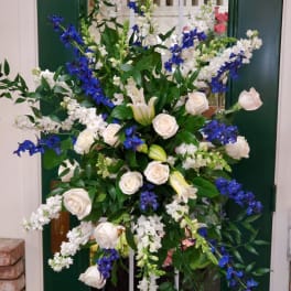 Tall floral spray with white roses, lilies, and blue flowers
