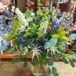 Mixed bouquet in a clear glass vase with blue, white, and yellow flowers