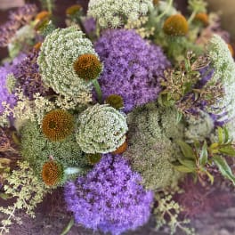 Purple and white floral bouquet with round orange-centered blooms