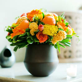 Orange and yellow floral arrangement in a dark vase