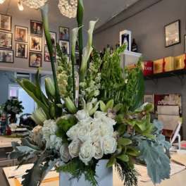 Tall white floral arrangement in a white box with calla lilies and roses