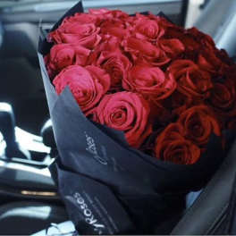 Bouquet of red roses wrapped in dark paper