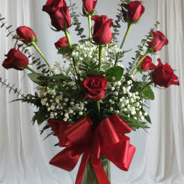 Tall bouquet of red roses with baby's breath in a glass vase and red ribbon