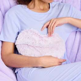 Person holding a fluffy heart-shaped plush pillow