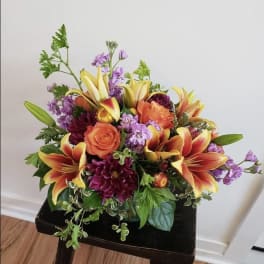 Bouquet of orange roses, lilies, and purple flowers