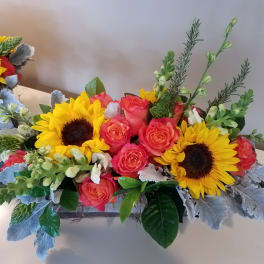 Bright bouquet with sunflowers and coral roses in a low rectangular container