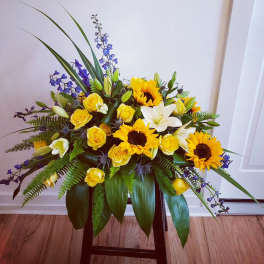 Yellow roses, sunflowers, and white lilies in a low arrangement