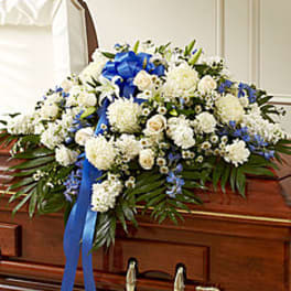 White floral casket spray with blue ribbon accents