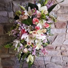 Tall standing floral spray with white lilies, pink roses, and lavender blooms