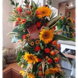 Large standing floral arrangement with sunflowers and red-orange roses