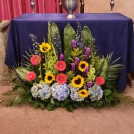 Colorful floral altar arrangement with sunflowers, gerbera daisies, and hydrangeas
