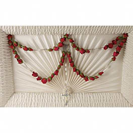 White casket with red rose garland draped across the lid