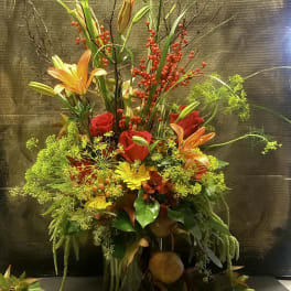 Tall floral arrangement with red roses, orange lilies, and red berry stems