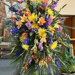 Large standing floral spray with yellow, orange, purple, and blue flowers
