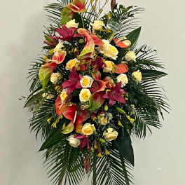 Standing floral spray with roses, anthuriums, and lilies in pink, cream, and red
