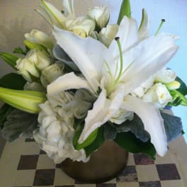 White lilies and roses arranged in a bronze vase