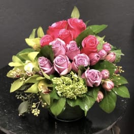 Pink and red rose bouquet with green hydrangea in a black vase