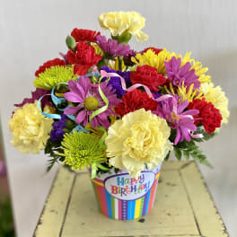 Colorful bouquet of carnations and daisies in a birthday container