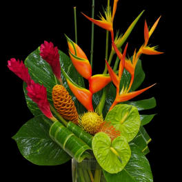 Tropical bouquet with orange bird-of-paradise and red ginger in a glass vase