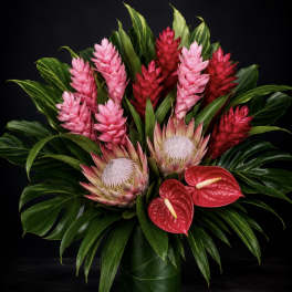 Tropical arrangement with pink and red blooms in a green vase